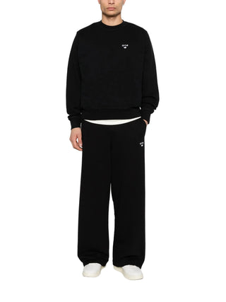 Person wearing a black sweatshirt and pants with a small logo by Arte Antwerp