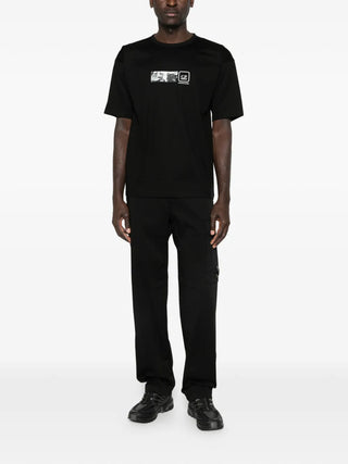 C.P. Company black cargo trousers with elasticated waistband, side flap pocket and logo detail. A versatile staple, available at our Lisbon store.
