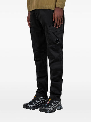 C.P. Company black cargo trousers with cargo pockets, logo patch and elasticated hem. A utilitarian staple, available at our Lisbon store.