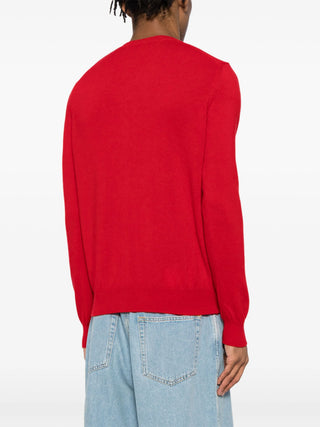 Comme Des Garçons PLAY red cardigan in 100% wool. Features a signature heart patch, ribbed V-neck, and long sleeves for a classic finish. 