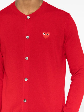 Comme Des Garçons PLAY red cardigan in 100% wool. Features a signature heart patch, ribbed V-neck, and long sleeves for a classic finish. 
