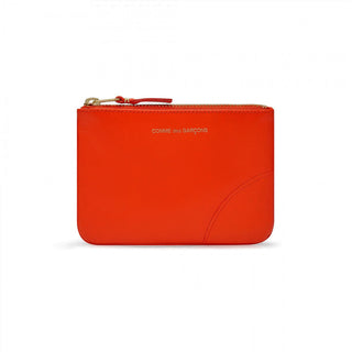 COMME DES GARÇONS WALLET vibrant orange leather wallet. Smooth calfskin, zip-around closure, and gold-tone logo print. Available at our Lisbon store. 