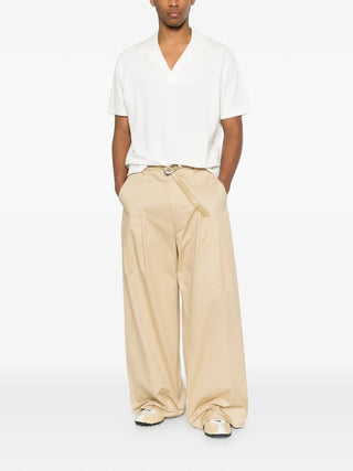 Comme des Garçons Homme brown pleated trousers with wide leg and tailored details. Refined fit and versatile style. Available at our Lisbon store.