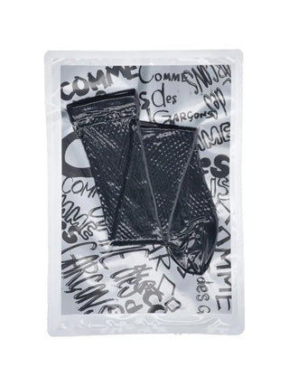 Comme des Garçons black logo socks with fish-net texture and subtle design — available at our Lisbon store.
