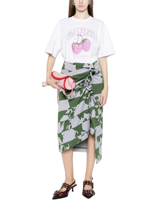 Person wearing a white t-shirt with Ganni graphics and a green and grey skirt.