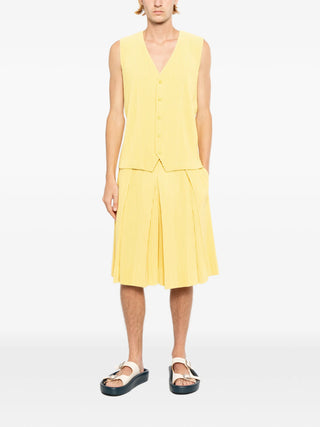 Homme Plissé Issey Miyake pleated trousers in button yellow with elasticated waist. Modern tailored fit, available at our Lisbon store.