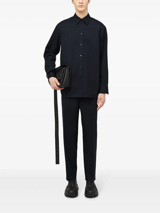 Jil Sander navy wool tapered trousers with elasticated waist, ruched detail and pressed crease. Refined fit, available at our Lisbon store.