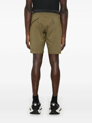 Person wearing olive green shorts by Klättermusen back view