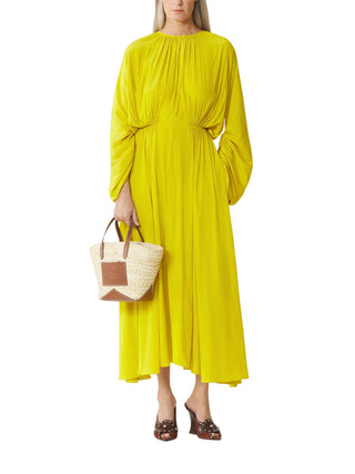 Woman wearing a bright yellow dress holding a straw bag by Lanvin