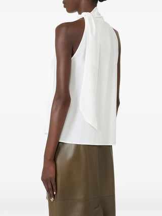 MAX MARA pussy-bow top. Sleeveless silk design with a feminine bow. Italian craftsmanship redefined. Available at our Lisbon store.