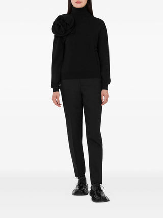 Moschino black flower-appliqué turtleneck with long sleeves and rose detail at the neck. A refined knit for day or night, available at our Lisbon store.