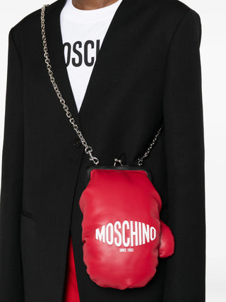 Moschino red boxing glove shoulder bag with chain strap, lace-up detail, and logo lettering. A bold statement accessory, available at our Lisbon store.