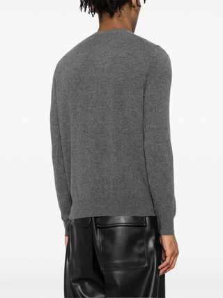 The cardigan by Comme des Garçons. Key details include, front button fastening, long sleeves, and round (crew) neck with the distictive heart patch logo