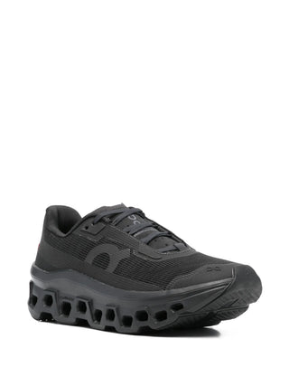 On Running Cloudmonster Void black sneakers with logo print and ridged rubber sole. Cushioned, everyday performance. Available at our Lisbon store.
