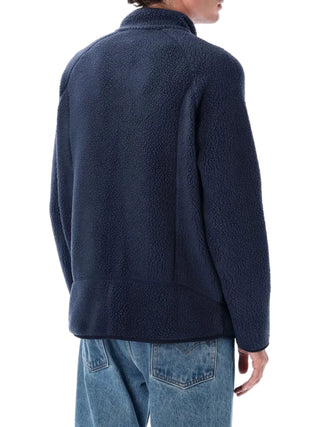 Person wearing a navy fleece jacket and blue jeans by Patagonia