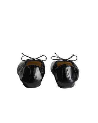 Gathered flat pump in black leather with a glossy sheen, rounded toe, rubber sole and in-built 10mm wedge for support and comfort. Grosgrain trim and tie.