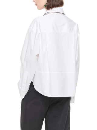 Person wearing a white long-sleeve shirt and dark pants.