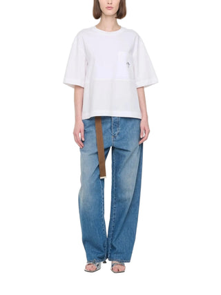 Person wearing a white short-sleeved t-shirt by Plan C and blue jeans with sandals. 