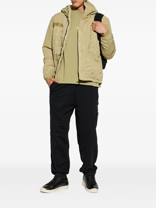 Stone Island hooded jacket with signature Compass patch. Functional hood, zip fastening, and technical fabric. Available at our Lisbon store. 