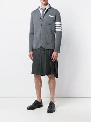 Thom Browne Classic Rise Backstrap skirt. A pleated knee-length silhouette in Super 120s wool with an adjustable backstrap and signature striped grosgrain trim.