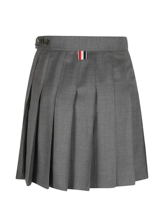Thom Browne thigh-length skirt. Engineered 4-Bar stripe, knife pleats, and a stepped dropped-back hem. Tailored in 100% wool with a grosgrain loop tab.