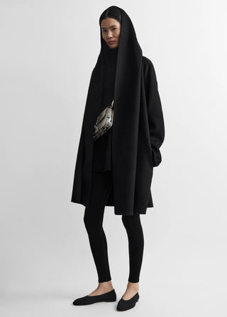 TOTEME hooded coat. Warm wool-blend felt, loose silhouette, generous hood, and patch pockets. Classic outerwear, available at our Lisbon store. 