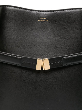 Black leather clutch with gold clasp and Toteme branding.
