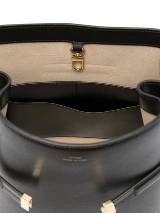 Close-up of a black handbag with gold hardware and internal compartments. 