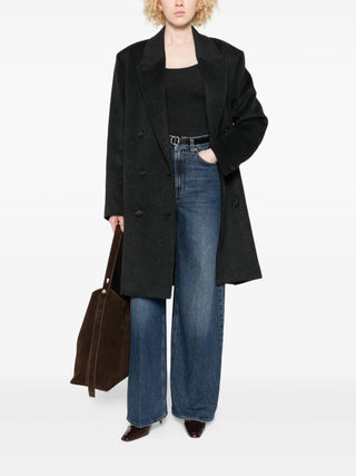 Person wearing a black coat and blue jeans holding a brown leather bag 