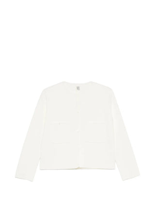 TOTEME's classic compact knit cardigan in white. Clean lines, pearl buttons, and a refined silhouette. A timeless layering piece. Available at our Lisbon store.