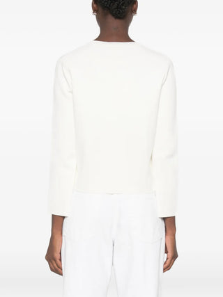 TOTEME's classic compact knit cardigan in white. Clean lines, pearl buttons, and a refined silhouette. A timeless layering piece. Available at our Lisbon store.