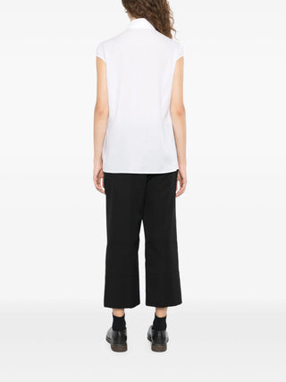 Person wearing a white sleeveless top by Yohji Yamamoto and black pants.
