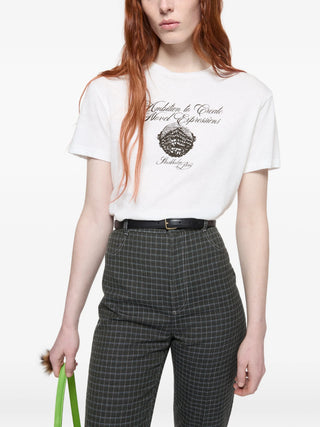 Person wearing a white t-shirt with text and graphics, paired with gray checkered pants by Acne Studios