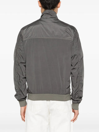 C.P. Company short jacket in Nycra-R. Crafted from ECONYL® regenerated stretch nylon with iconic lens detail. Garment dyed. Regular fit. 