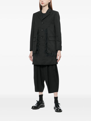 Person wearing a black coat and pants by Comme DES Garcons