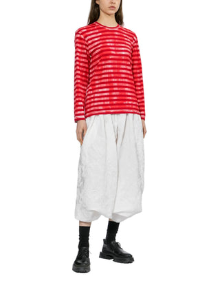 Person wearing a red and white striped shirt with a white cropped pants and black shoes