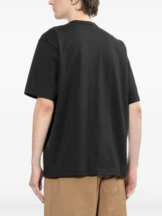 Person wearing a black t-shirt by Comme Des Garcons Homme 