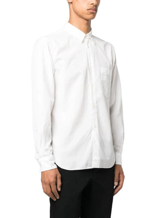 Person wearing a white long-sleeve shirt with black pants. 