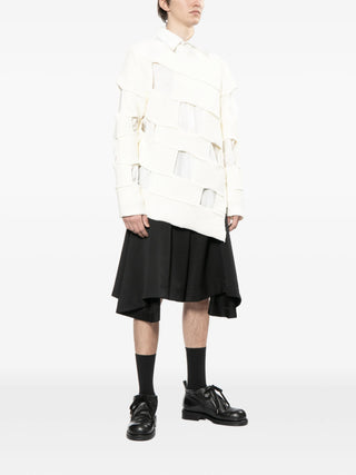 Person wearing a white coat, black skirt, and black shoes