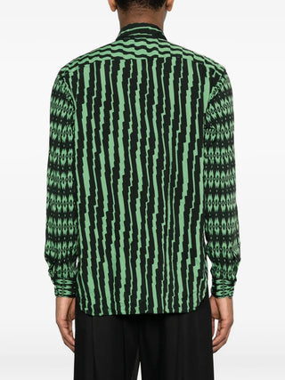 Person wearing a green and black patterned shirt on a white background