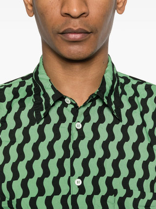 Person wearing a green and black patterned shirt against a white background
