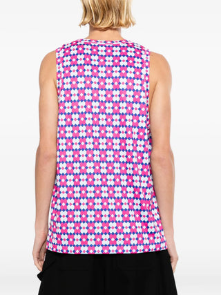 Person wearing a sleeveless top with a pink and white geometric pattern on a white background