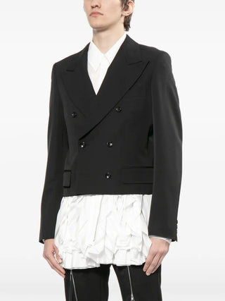 Person wearing a black double-breasted jacket over a white shirt on a white background