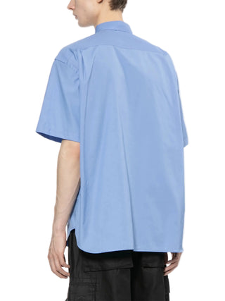 Person wearing a light blue short-sleeve shirt by Comme des Garcons