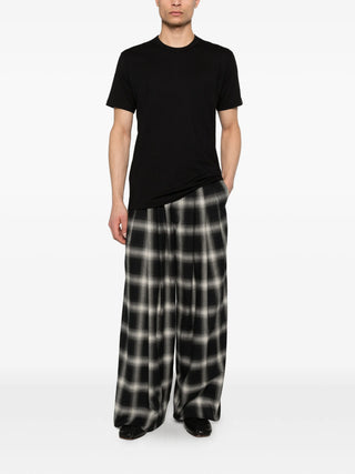 Person wearing a black t-shirt and wide-leg checkered pants 