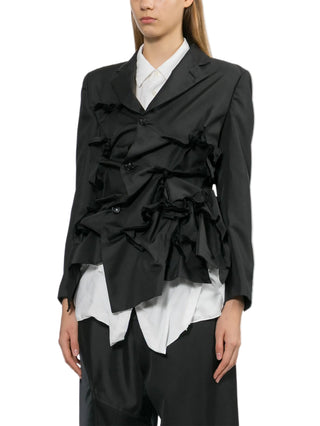 Person wearing a black jacket over a white shirt with black pants