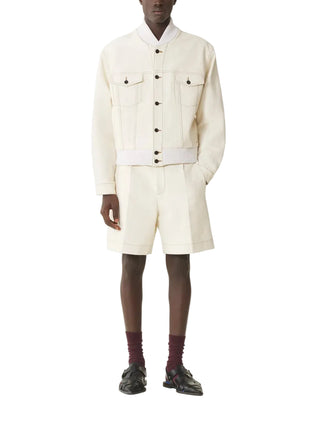 Person wearing a cream-colored outfit with a jacket and shorts on a white background