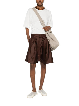 Person wearing a white top and brown leather shorts by Dusan with a beige bag