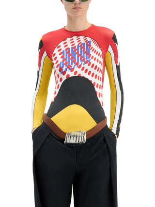 Person wearing a colorful printed long-sleeved top by Jean Paul Gaultier with black pants.