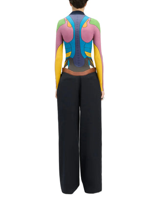 Person wearing a colorful, abstract-patterned long-sleeved top with black pants by Jean Paul Gautier
